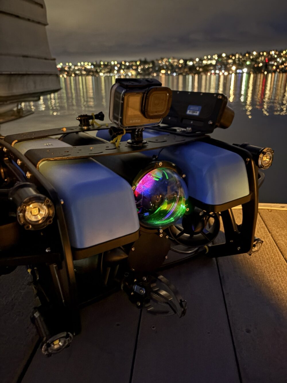BlueROV2 staged for a night dive with city lights reflected on the water