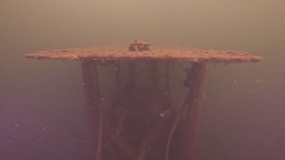 Submerged wreck structure silhouetted underwater